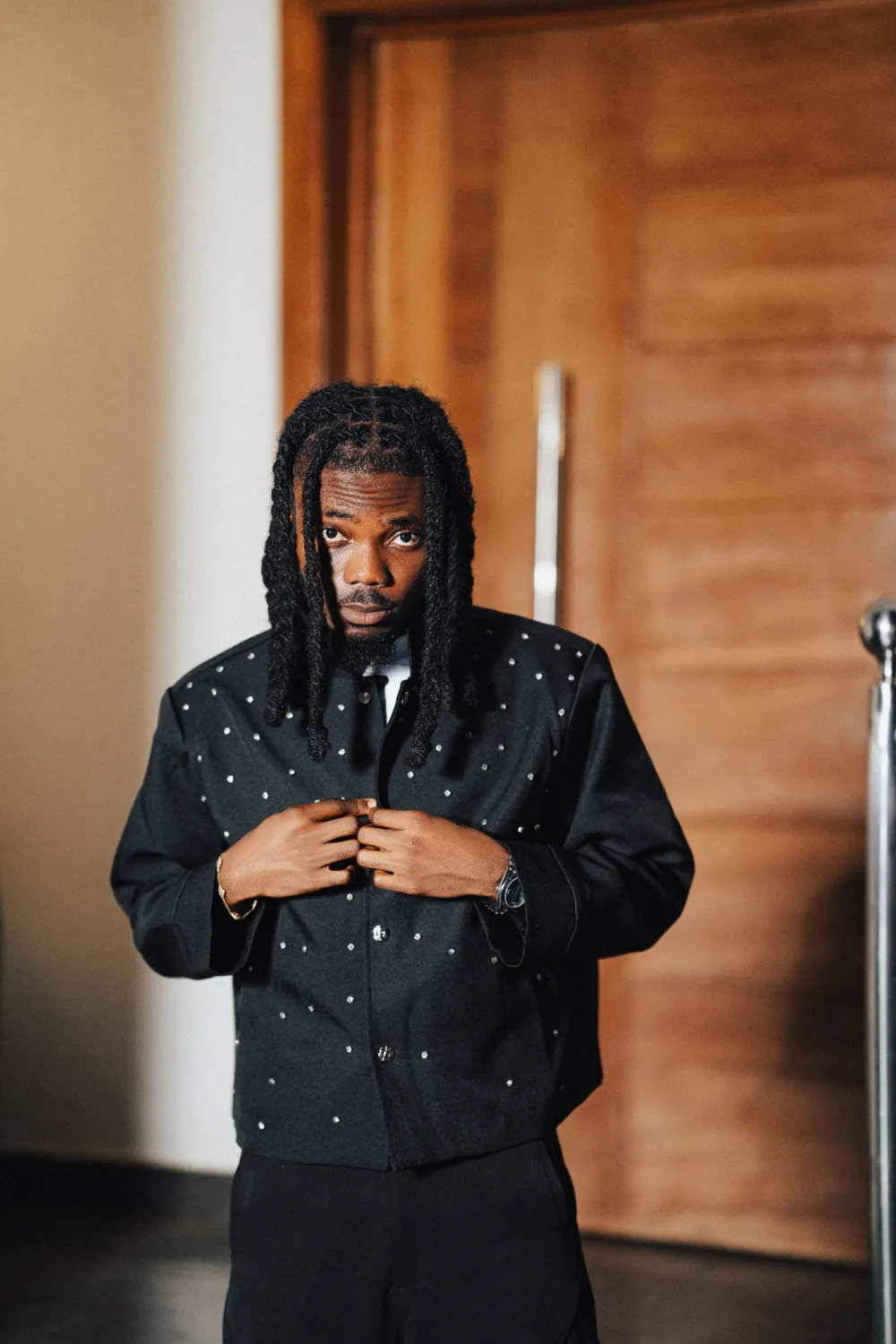 Emmy Blaq in a studded black shirt, buttoning it up